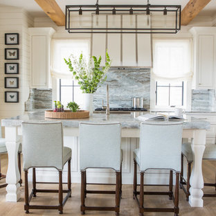 This is an example of a beach style l-shaped kitchen in Miami with shaker cabinets, white cabinets, multi-coloured splashback, stone slab splashback, stainless steel appliances, light hardwood floors, with island, beige floor and multi-coloured benchtop.