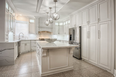 Large transitional u-shaped limestone floor and beige floor eat-in kitchen photo in Toronto with an undermount sink, raised-panel cabinets, white cabinets, marble countertops, white backsplash, marble backsplash, stainless steel appliances, an island and white countertops