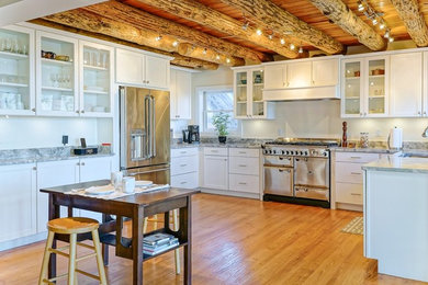 ワシントンD.C.にある高級な広いラスティックスタイルのおしゃれなキッチン (シングルシンク、シェーカースタイル扉のキャビネット、白いキャビネット、御影石カウンター、シルバーの調理設備、無垢フローリング、茶色い床) の写真
