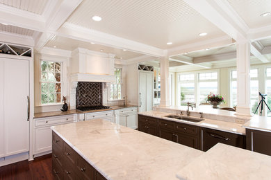 Exempel på ett stort klassiskt kök, med en undermonterad diskho, luckor med profilerade fronter, vita skåp, marmorbänkskiva, brunt stänkskydd, stänkskydd i keramik, integrerade vitvaror, mellanmörkt trägolv och flera köksöar
