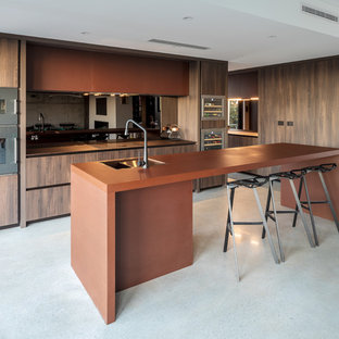 Inspiration for a contemporary l-shaped kitchen in Perth with an undermount sink, flat-panel cabinets, dark wood cabinets, stainless steel appliances, concrete floors, with island, grey floor and brown benchtop.
