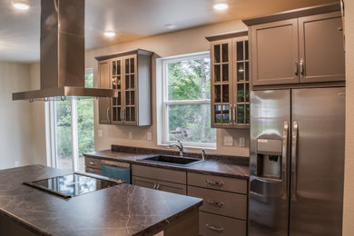 Example of a mid-sized classic l-shaped medium tone wood floor and brown floor eat-in kitchen design in Other with an undermount sink, shaker cabinets, gray cabinets, laminate countertops, stainless steel appliances, an island and multicolored countertops