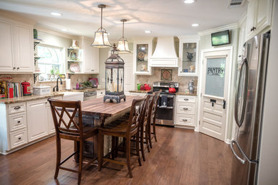 Mid-sized elegant u-shaped dark wood floor and brown floor eat-in kitchen photo in New Orleans with a farmhouse sink, raised-panel cabinets, white cabinets, granite countertops, beige backsplash, stone tile backsplash, stainless steel appliances, an island and beige countertops