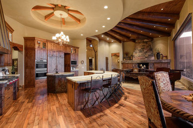 Example of a mid-sized southwest u-shaped light wood floor eat-in kitchen design in Salt Lake City with a drop-in sink, raised-panel cabinets, dark wood cabinets, concrete countertops, stainless steel appliances and an island