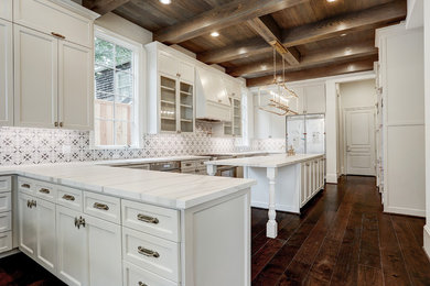 Example of a large farmhouse u-shaped dark wood floor and brown floor enclosed kitchen design in Houston with recessed-panel cabinets, white cabinets, quartzite countertops, multicolored backsplash, ceramic backsplash, an island and white countertops