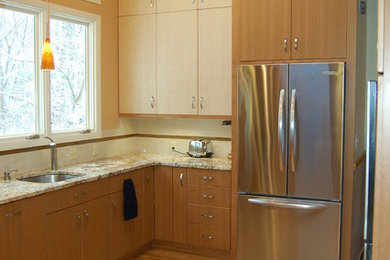 Exempel på ett stort modernt kök och matrum, med en undermonterad diskho, släta luckor, skåp i ljust trä, granitbänkskiva, beige stänkskydd, stänkskydd i keramik, rostfria vitvaror och ljust trägolv
