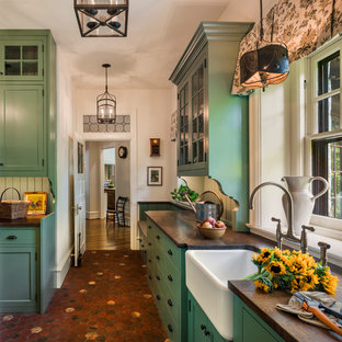 Traditional separate kitchen in Philadelphia with a farmhouse sink, shaker cabinets, green cabinets, terra-cotta floors, red floor and wood benchtops.