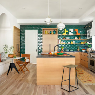 Large eclectic eat-in kitchen photos - Inspiration for a large eclectic l-shaped light wood floor and gray floor eat-in kitchen remodel in Minneapolis with flat-panel cabinets, light wood cabinets, soapstone countertops, an island, green backsplash, glass tile backsplash, paneled appliances and gray countertops