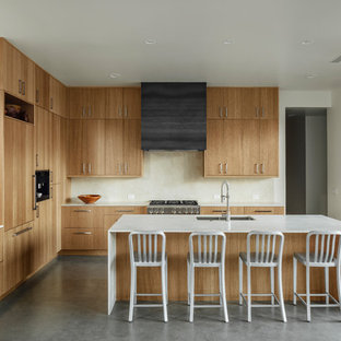 Immagine di una cucina stile americano con lavello sottopiano, ante lisce, top in marmo, paraspruzzi beige, paraspruzzi in marmo, elettrodomestici da incasso, pavimento in cemento, isola, top beige, ante in legno chiaro e pavimento grigio
