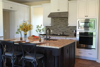 Eat-in kitchen - large traditional eat-in kitchen idea in Phoenix with granite countertops, gray backsplash, stone tile backsplash, black appliances and an island