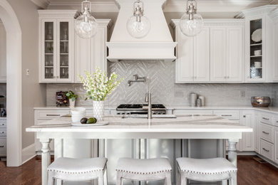 Inspiration for a large traditional l-shaped kitchen/diner in Charlotte with a submerged sink, white cabinets, engineered stone countertops, grey splashback, porcelain splashback, stainless steel appliances, dark hardwood flooring, an island, brown floors, white worktops and raised-panel cabinets.