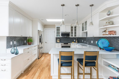 Example of a mid-sized u-shaped light wood floor and beige floor eat-in kitchen design in Vancouver with an undermount sink, recessed-panel cabinets, white cabinets, quartzite countertops, black backsplash, glass tile backsplash, stainless steel appliances, a peninsula and white countertops