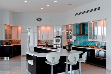 Example of a mid-sized trendy u-shaped linoleum floor and white floor enclosed kitchen design in New York with an undermount sink, glass-front cabinets, white cabinets, solid surface countertops, blue backsplash, ceramic backsplash, paneled appliances and an island
