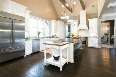 Mid-sized farmhouse l-shaped dark wood floor and brown floor open concept kitchen photo in Sacramento with a farmhouse sink, shaker cabinets, white cabinets, solid surface countertops, white backsplash, subway tile backsplash, stainless steel appliances and an island