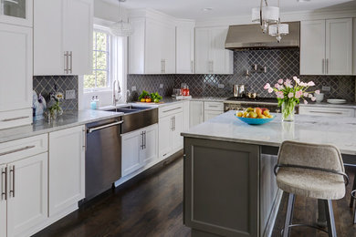 Large transitional u-shaped dark wood floor and brown floor eat-in kitchen photo in Chicago with a farmhouse sink, recessed-panel cabinets, white cabinets, marble countertops, gray backsplash, porcelain backsplash, stainless steel appliances and an island