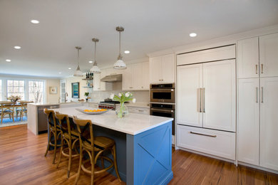 Große Klassische Küche in L-Form mit Landhausspüle, Schrankfronten im Shaker-Stil, weißen Schränken, Küchenrückwand in Weiß, Küchengeräten aus Edelstahl, Kücheninsel, braunem Boden und weißer Arbeitsplatte in Boston