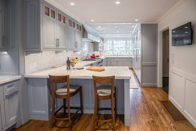 Example of a mid-sized transitional u-shaped medium tone wood floor enclosed kitchen design in Boston with an undermount sink, shaker cabinets, gray cabinets, quartzite countertops, white backsplash, stone slab backsplash, stainless steel appliances and a peninsula