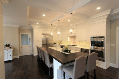 Eat-in kitchen - large transitional l-shaped eat-in kitchen idea in Boston with a farmhouse sink, recessed-panel cabinets, white cabinets, wood countertops, stainless steel appliances and an island