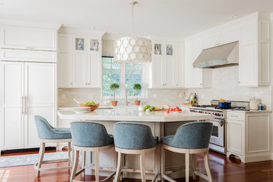 Example of a mid-sized transitional l-shaped medium tone wood floor and brown floor enclosed kitchen design in Boston with a farmhouse sink, recessed-panel cabinets, white cabinets, quartzite countertops, beige backsplash, stone slab backsplash, paneled appliances, an island and beige countertops