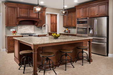Kitchen pantry - mid-sized traditional l-shaped ceramic tile and beige floor kitchen pantry idea in New York with a farmhouse sink, raised-panel cabinets, dark wood cabinets, granite countertops, gray backsplash, glass tile backsplash, stainless steel appliances, an island and brown countertops