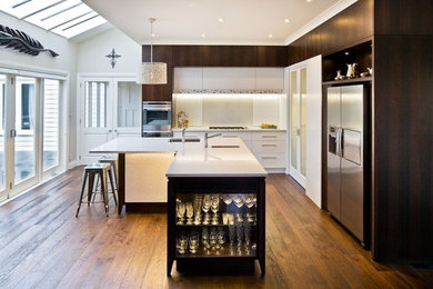 Mid-sized minimalist l-shaped dark wood floor eat-in kitchen photo in Wellington with an undermount sink, white cabinets, quartz countertops, white backsplash, stainless steel appliances and an island