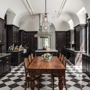 Inspiration for a mediterranean eat-in kitchen in Miami with a farmhouse sink, raised-panel cabinets, dark wood cabinets and with island.