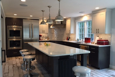 Inspiration for a large transitional l-shaped light wood floor and brown floor kitchen remodel in Portland Maine with an undermount sink, shaker cabinets, dark wood cabinets, white backsplash, marble backsplash, stainless steel appliances, an island and white countertops