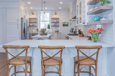 Large transitional l-shaped eat-in kitchen photo in Philadelphia with glass-front cabinets, white cabinets, marble countertops and an island