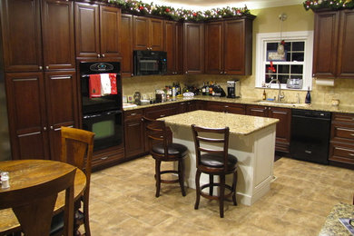 Ejemplo de cocinas en L clásica de tamaño medio con fregadero bajoencimera, puertas de armario de madera en tonos medios, una isla y electrodomésticos negros