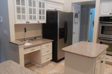 This is an example of a medium sized classic galley kitchen/diner in Orlando with raised-panel cabinets, white cabinets and stainless steel appliances.