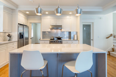 Example of a mid-sized minimalist l-shaped light wood floor eat-in kitchen design with an undermount sink, white cabinets, gray backsplash, stainless steel appliances and an island