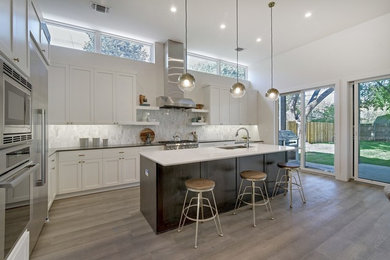 Large light wood floor and gray floor kitchen photo in Austin with white backsplash, black countertops, an undermount sink, white cabinets, quartz countertops, porcelain backsplash, stainless steel appliances and an island