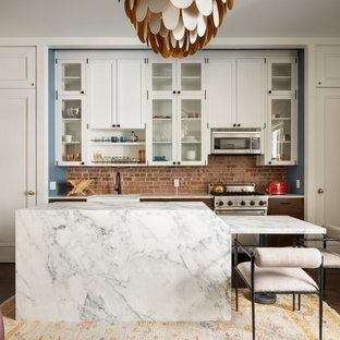 Small transitional eat-in kitchen inspiration - Inspiration for a small transitional dark wood floor and brown floor eat-in kitchen remodel in New York with a farmhouse sink, shaker cabinets, white cabinets, marble countertops, brick backsplash, stainless steel appliances, an island and white countertops