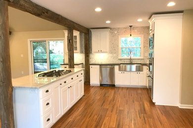 Inspiration for a large transitional medium tone wood floor and brown floor open concept kitchen remodel in Atlanta with shaker cabinets, white cabinets, granite countertops, an island, a farmhouse sink, gray backsplash, marble backsplash and stainless steel appliances