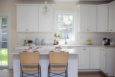 Enclosed kitchen - mid-sized transitional l-shaped medium tone wood floor enclosed kitchen idea in Boston with shaker cabinets, white cabinets, marble countertops, white backsplash, subway tile backsplash, stainless steel appliances and an island