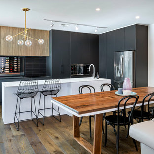 This is an example of a contemporary galley eat-in kitchen in Adelaide with black cabinets, black splashback, with island, flat-panel cabinets, subway tile splashback and medium hardwood floors.