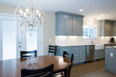 Eat-in kitchen - large contemporary l-shaped brown floor and porcelain tile eat-in kitchen idea in Detroit with a farmhouse sink, shaker cabinets, blue cabinets, an island, granite countertops, white backsplash, ceramic backsplash and stainless steel appliances