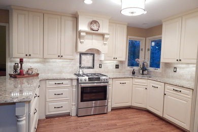 Inspiration for a mid-sized timeless u-shaped medium tone wood floor eat-in kitchen remodel in Detroit with an undermount sink, recessed-panel cabinets, white cabinets, marble countertops, white backsplash, ceramic backsplash, stainless steel appliances and a peninsula
