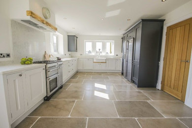 Photo of a large farmhouse u-shaped kitchen/diner in Other with a belfast sink, shaker cabinets, grey cabinets, quartz worktops, grey splashback, limestone flooring and no island.