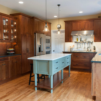 Arts and crafts u-shaped kitchen photo in Philadelphia with shaker cabinets, dark wood cabinets, white backsplash, subway tile backsplash and stainless steel appliances