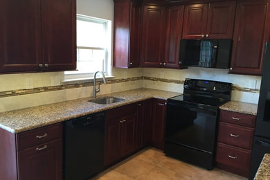 Inspiration for a mid-sized timeless l-shaped travertine floor eat-in kitchen remodel in Philadelphia with an undermount sink, raised-panel cabinets, dark wood cabinets, quartzite countertops, beige backsplash, subway tile backsplash, black appliances and no island