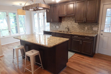 Example of a medium tone wood floor eat-in kitchen design in Other with gray cabinets, granite countertops, gray backsplash, mosaic tile backsplash and an island