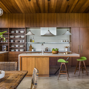 Asian eat-in kitchen inspiration - Example of an u-shaped concrete floor and gray floor eat-in kitchen design in San Francisco with an undermount sink, flat-panel cabinets, dark wood cabinets, white backsplash, stainless steel appliances and an island