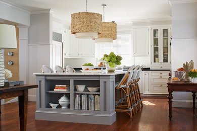 Example of a mid-sized beach style u-shaped medium tone wood floor and brown floor kitchen design in Boston with an undermount sink, recessed-panel cabinets, white cabinets, quartz countertops, white backsplash, wood backsplash, paneled appliances and an island