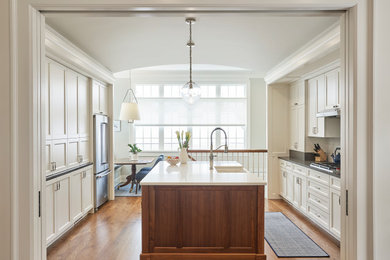 Inspiration for a large timeless u-shaped dark wood floor and brown floor eat-in kitchen remodel in Chicago with an undermount sink, shaker cabinets, white cabinets, solid surface countertops, white backsplash, ceramic backsplash, stainless steel appliances, white countertops and an island