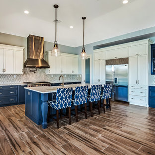 Inspiration for a large transitional l-shaped open plan kitchen in Tampa with a farmhouse sink, shaker cabinets, white cabinets, recycled glass benchtops, multi-coloured splashback, porcelain splashback, stainless steel appliances, porcelain floors and with island.