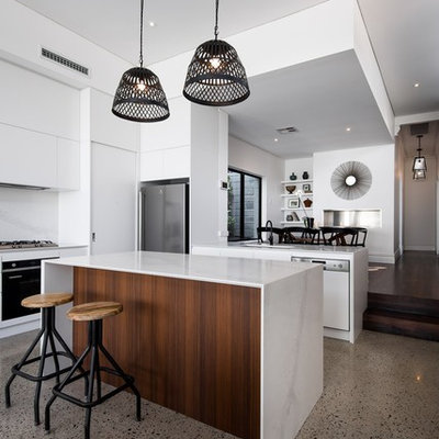 Example of a mid-sized trendy l-shaped concrete floor eat-in kitchen design in Perth with white cabinets, white backsplash, stone slab backsplash, an island, an undermount sink, quartz countertops and stainless steel appliances