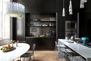 Große Küche mit Einbauwaschbecken, schwarzen Schränken, Marmor-Arbeitsplatte, Küchengeräten aus Edelstahl, braunem Holzboden und grauer Arbeitsplatte in London