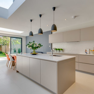 Large contemporary galley open plan kitchen in London with flat-panel cabinets, granite worktops, an island, white worktops, beige cabinets, beige floors, a submerged sink and beige splashback.