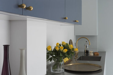 Inspiration for a medium sized contemporary kitchen/diner in London with a built-in sink, flat-panel cabinets, blue cabinets, stainless steel worktops and metallic splashback.